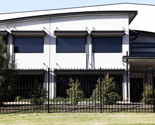A photo of a commercial building with garrison fencing at the front.